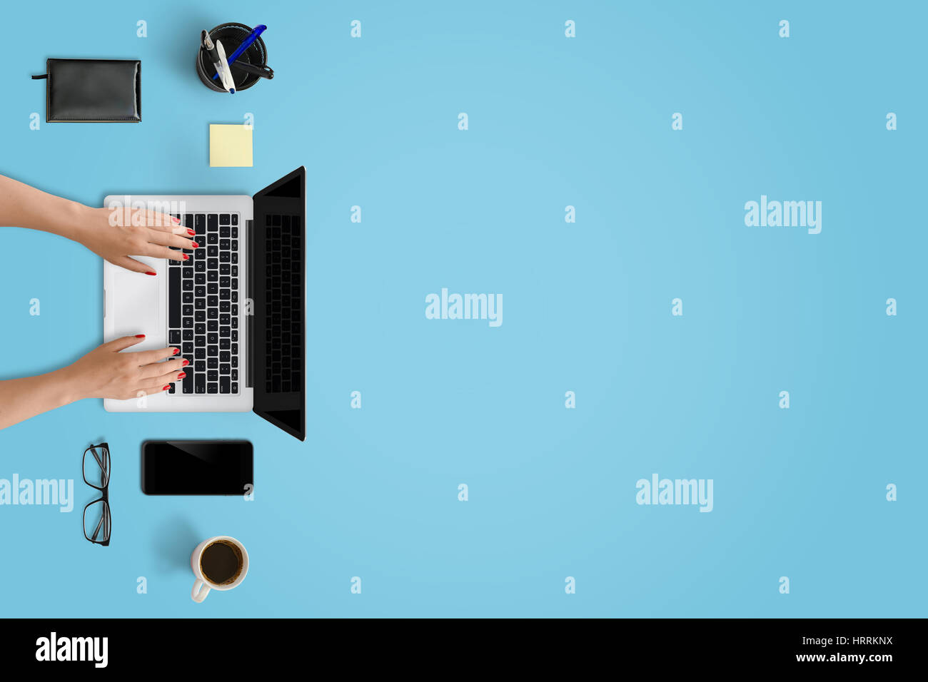 Laptop, smart phone and office supplies with free space for text. Top view of modern blue desk. Stock Photo