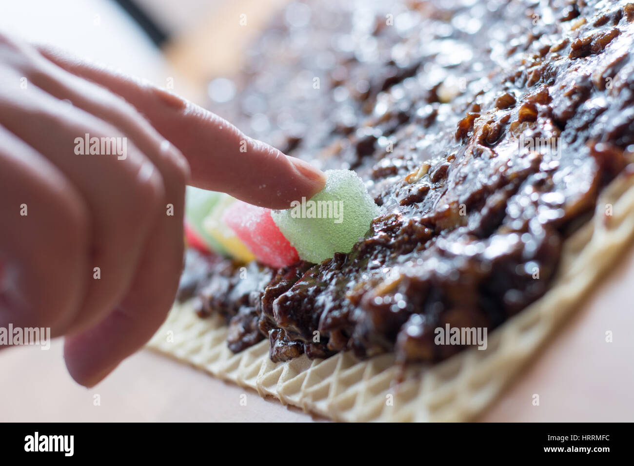 Chocolate topping with wallnuts on cake crust for rolled chocolate cake with jelly candies Stock Photo