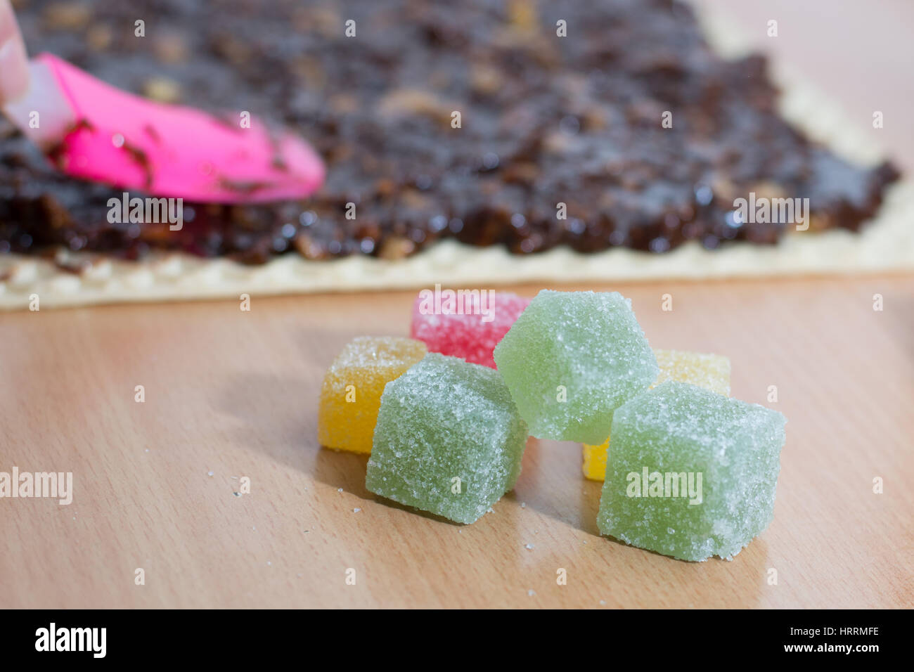 Chocolate topping with wallnuts on cake crust for rolled chocolate cake with jelly candies Stock Photo