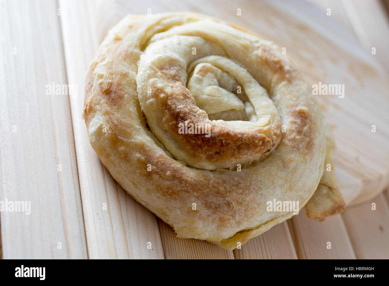 Freshly baked spiral cheese pie on the wooden plate ready to be cuted Stock Photo