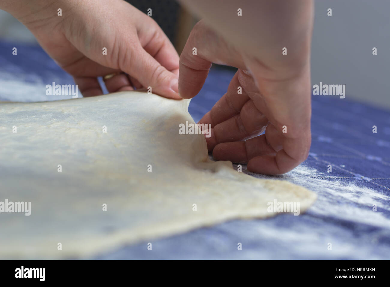 Creating homemade Phyllo or strudel dough on a home table cloth for cheese pie or other kind of traditional pastry. Stock Photo