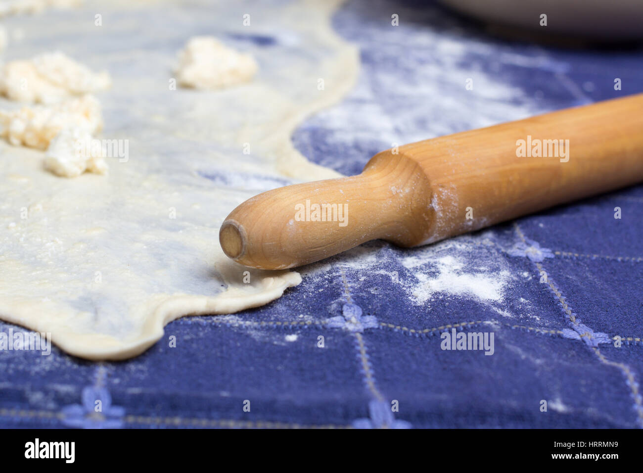 Homemade Phyllo or strudel dough with cheese and rolling pin on a home table cloth ready for cheese burek pie or other kind of traditional pastry. Stock Photo
