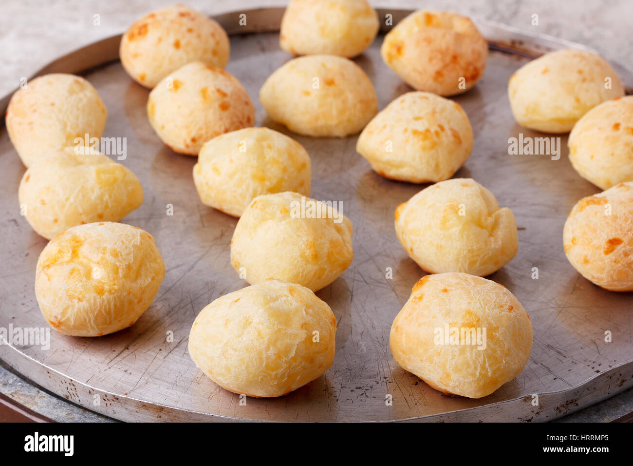 Cooking brazilian snack cheese bread (pao de queijo) on oven-tray. Selective focus Stock Photo