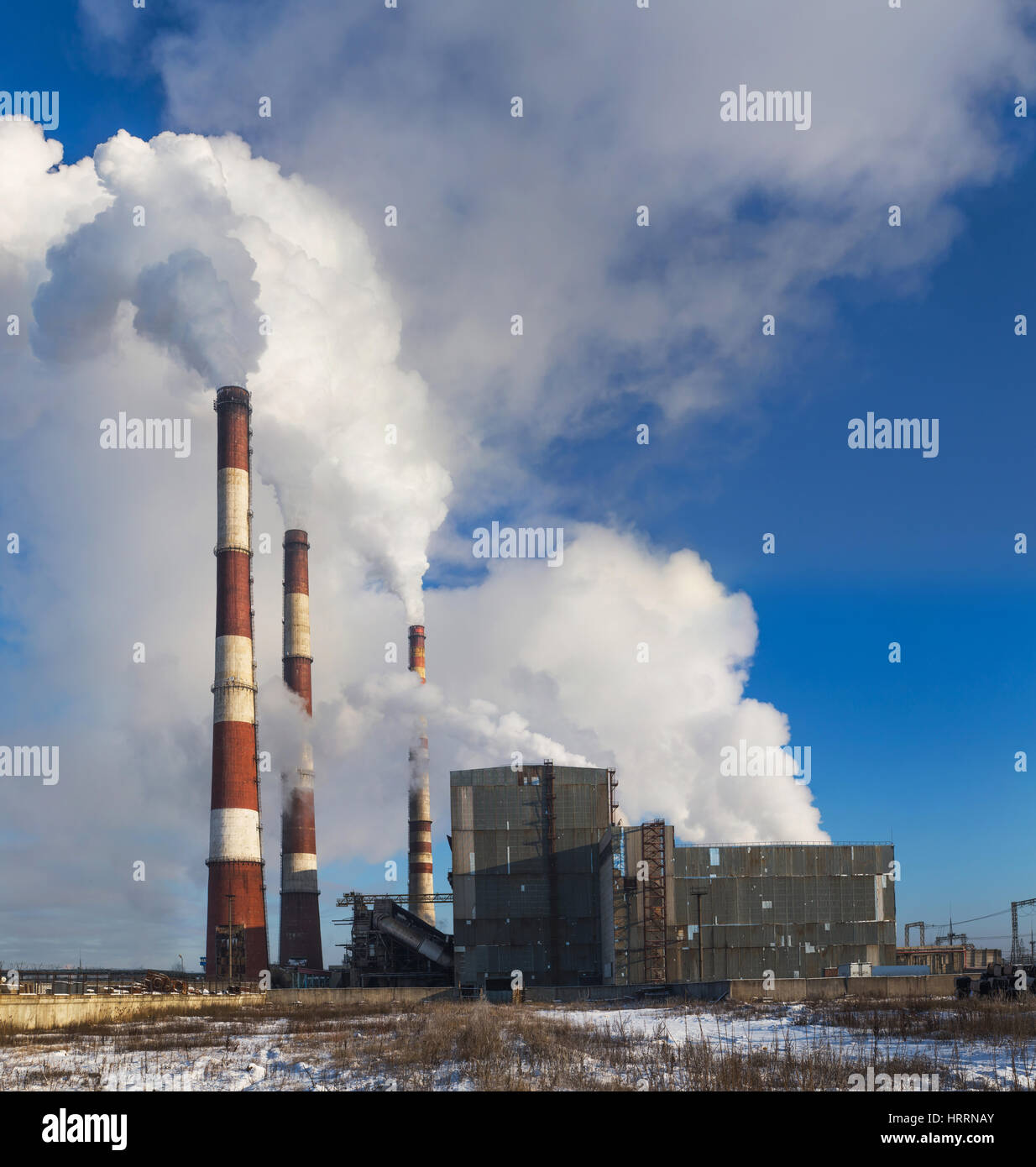 Power plant on blue sky background. Common view of coal plant. Perfect environment background. Smoke of power plants pollute environment. Stock Photo