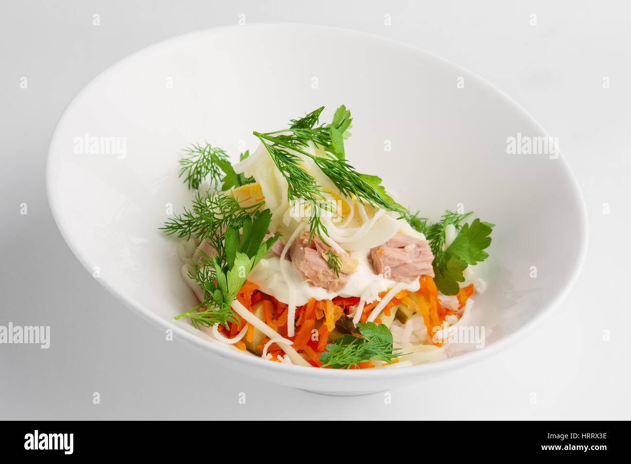 Plate with tuna salad with eggs, carrot, onion and mayonnaise on white background Stock Photo