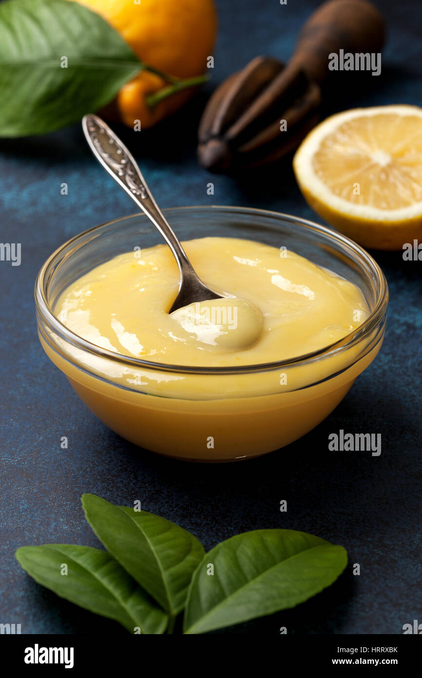 lemon curd in a glass bowl, fresh lemons, juicer on a blue background