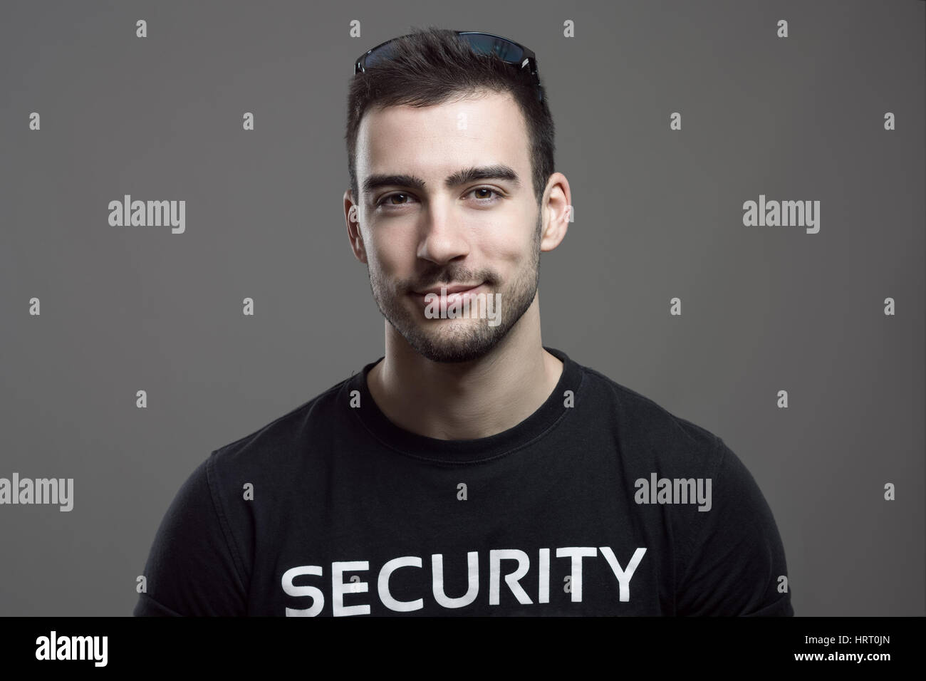 Friendly smiling security guard looking at camera over dark gray studio