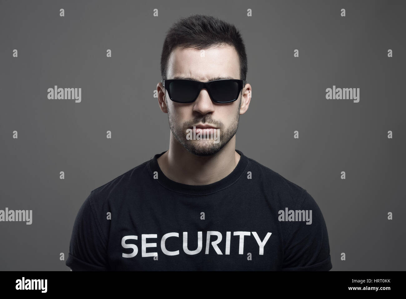 Serious moody portrait of security guard wearing sunglasses looking at