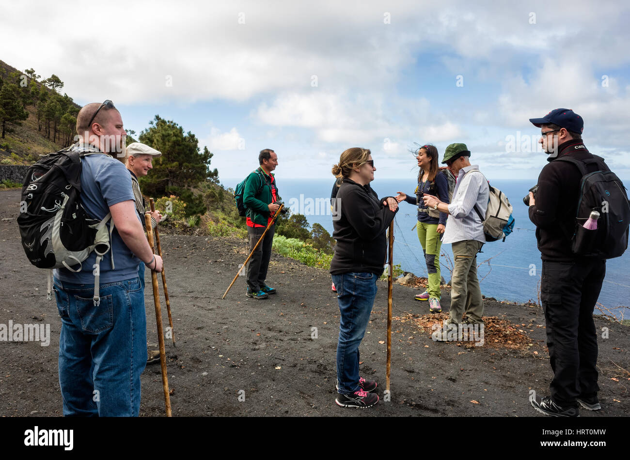 Hiking Trail in Fuencaliente. La Palma.   The tourists stop to enjoy the views from the mountain side looking out to the sea.  It's a bright hazy day with fast moving clouds. Stock Photo