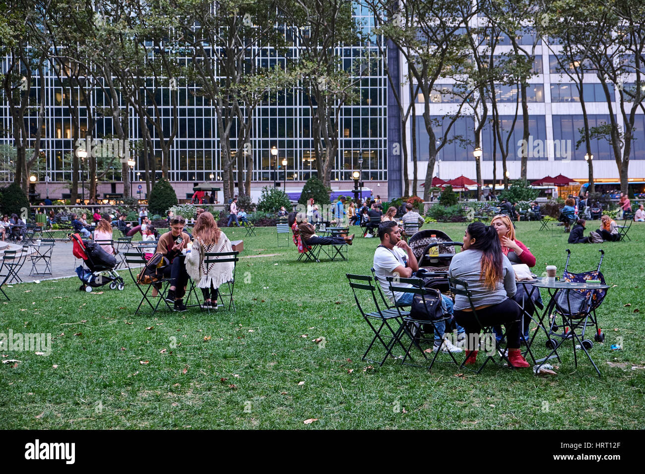 NEW YORK CITY - SEPTEMBER 26, 2016: People sitting in Bryant Park at small cafe tables and chairs, drinking and eating Stock Photo