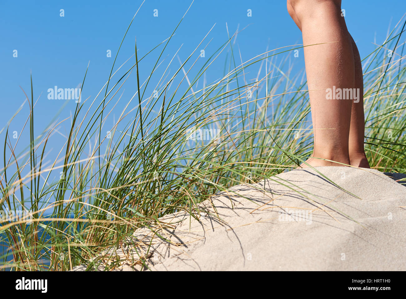Legs of a young woman standing in the sand dunes Stock Photo