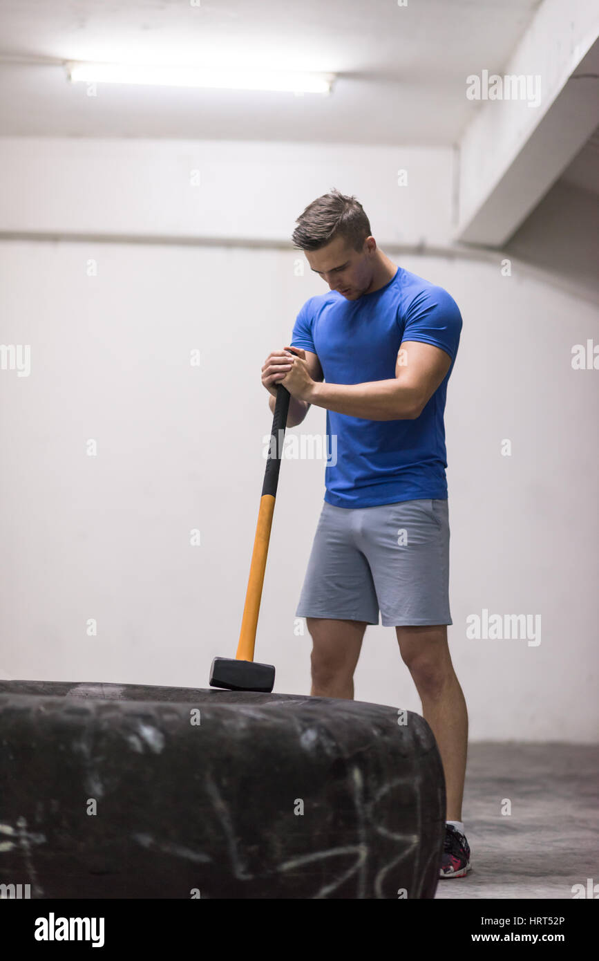 Sledgehammer Tire Hits young muscular man workout at gym with hammer