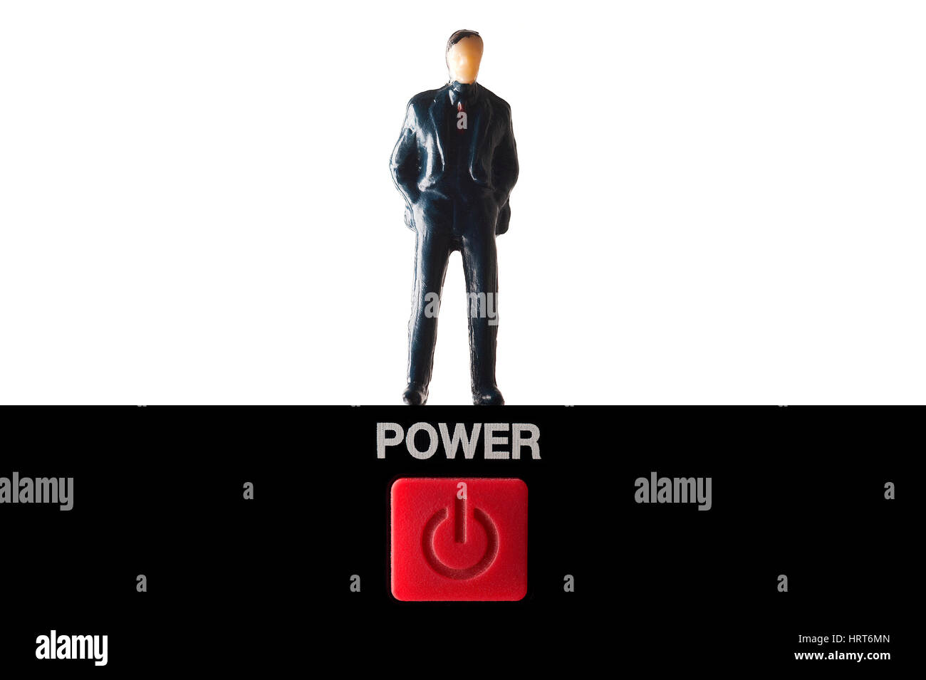Miniature figure in suit standing on power button against white background Stock Photo