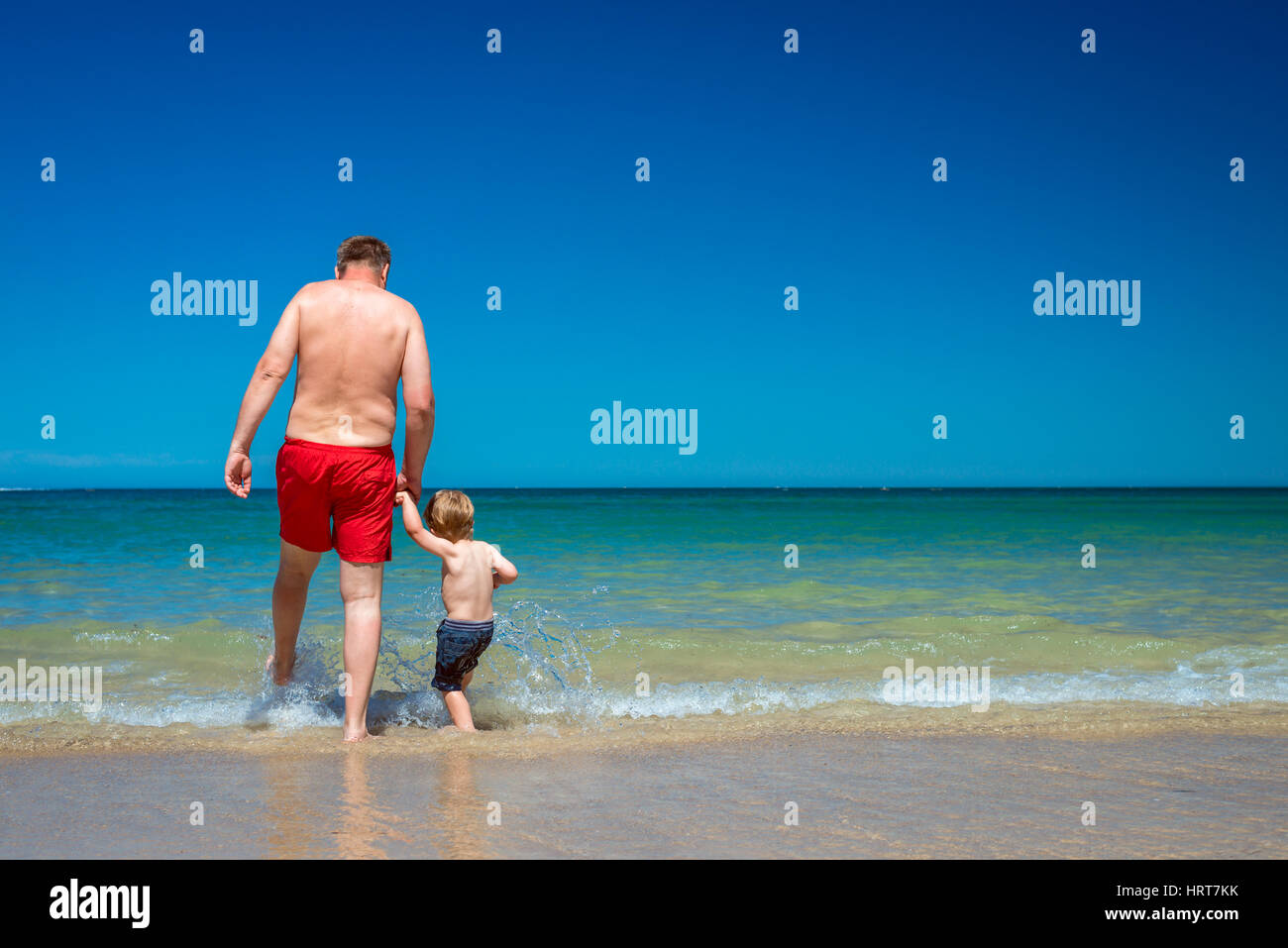 Grandfather with grandson holding hands on beach on a day Stock Photo