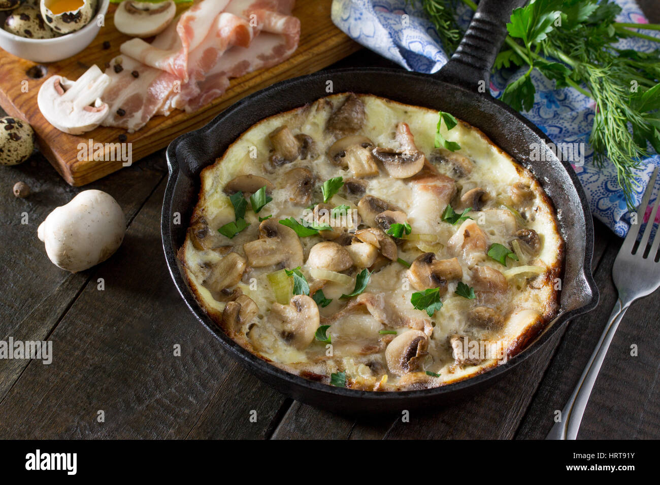 Omelette from quail eggs with ham and bacon in a cast iron frying pan