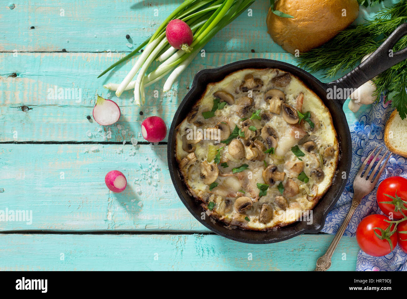 Omelette from quail eggs with ham and bacon in a cast iron frying pan