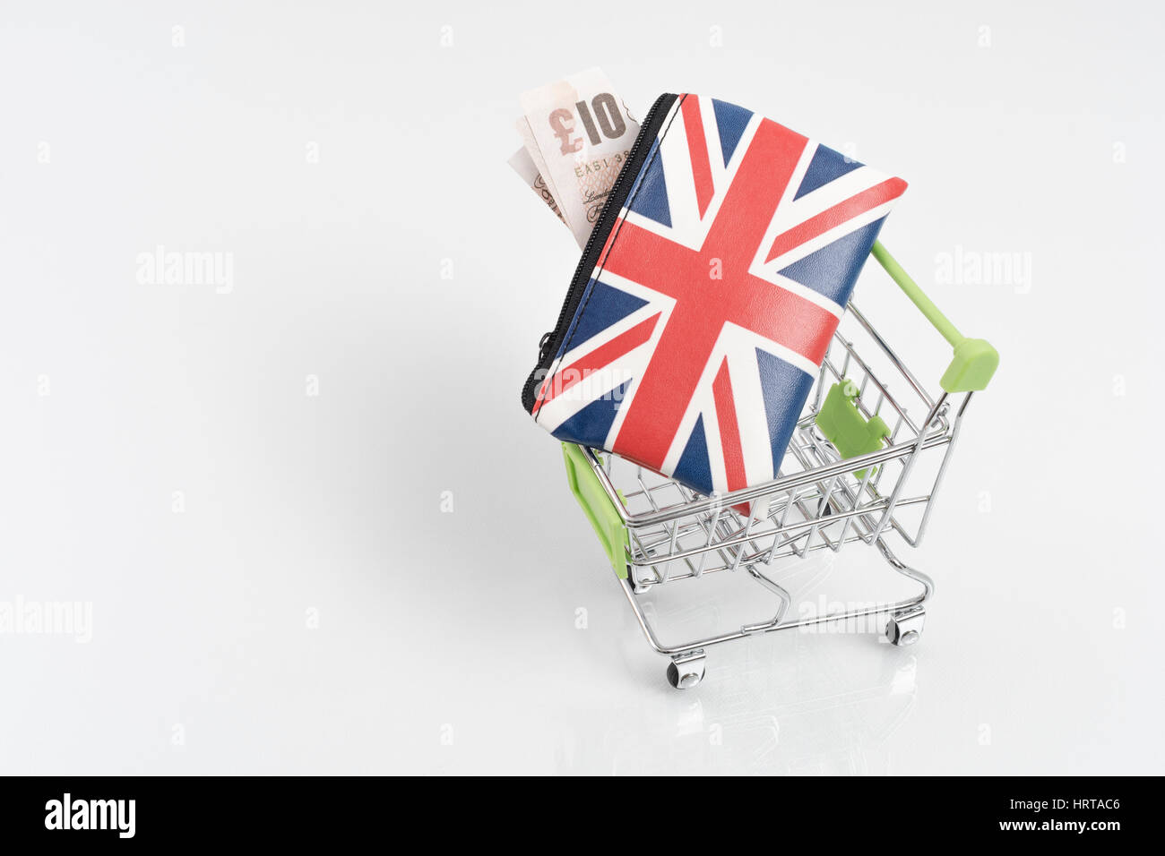 Union Jack coin purse / wallet with £10 banknote in a toy shopping trolley. Metaphor for UK consumer spending, economy and retail/high street sales Stock Photo