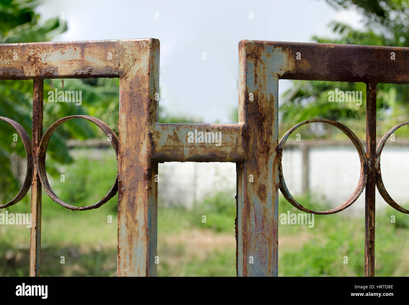 Green metal fence become rusted through years of disregard. Stock Photo