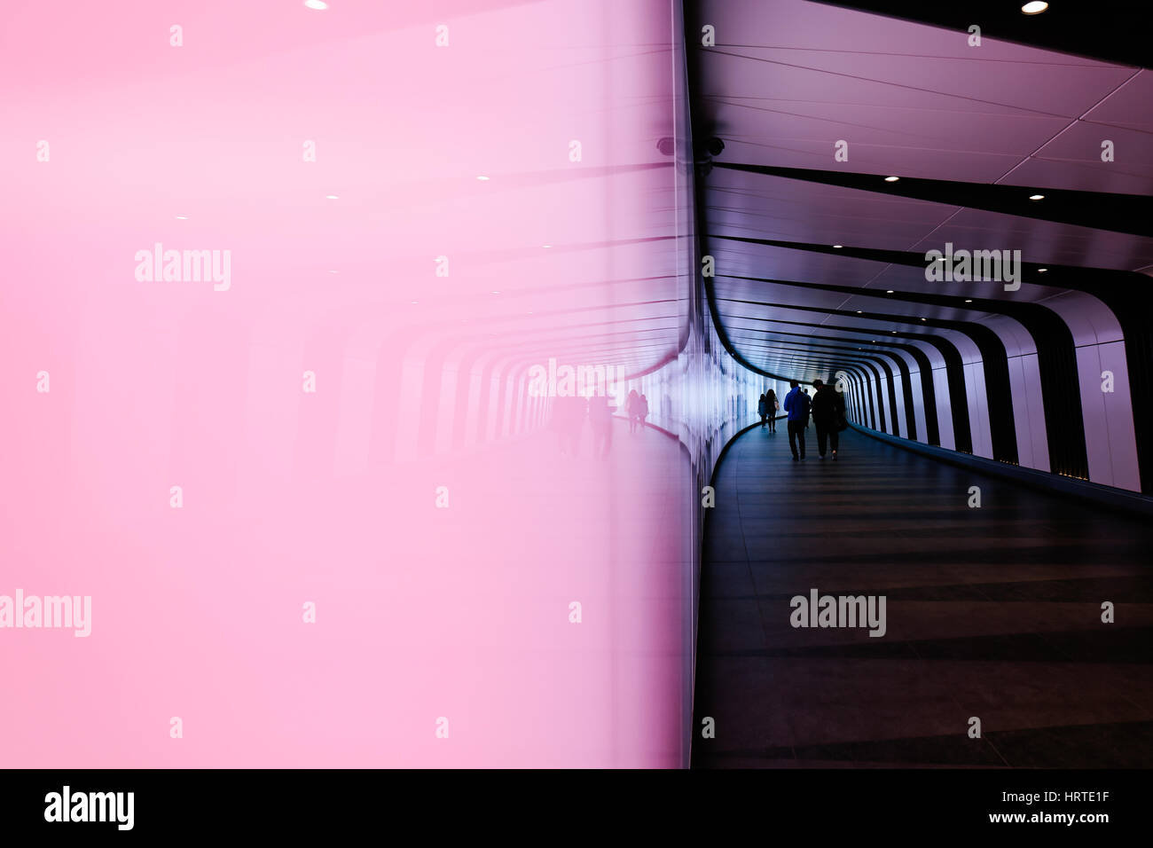 Reflection of people walking through futuristic looking pedestrian tunnel featuring an LED integrated light wall in Granary Square exit from Kings Cro Stock Photo