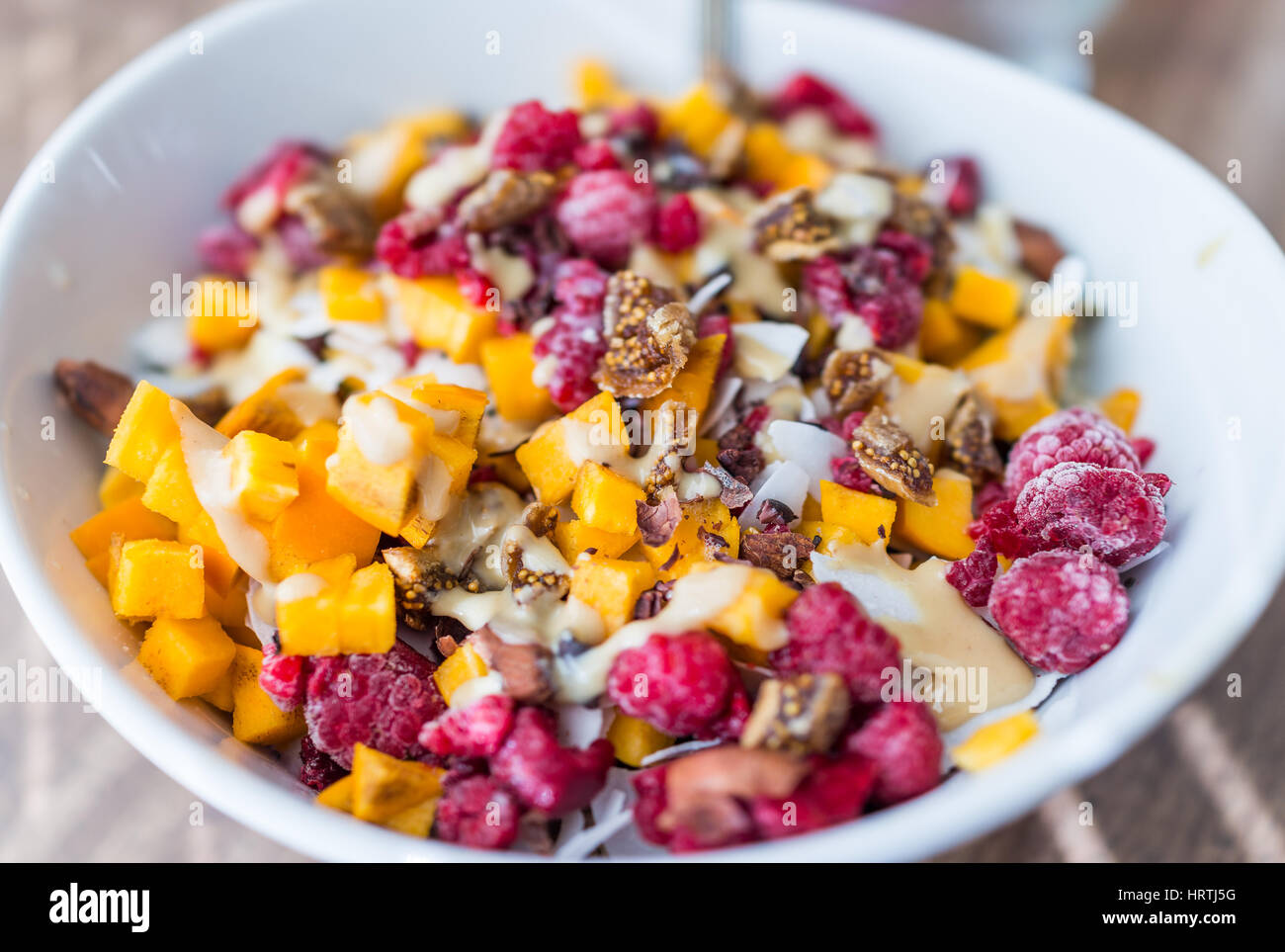 Chopped persimmon, raspberries, and figs in bowl with tahini macro closeup Stock Photo