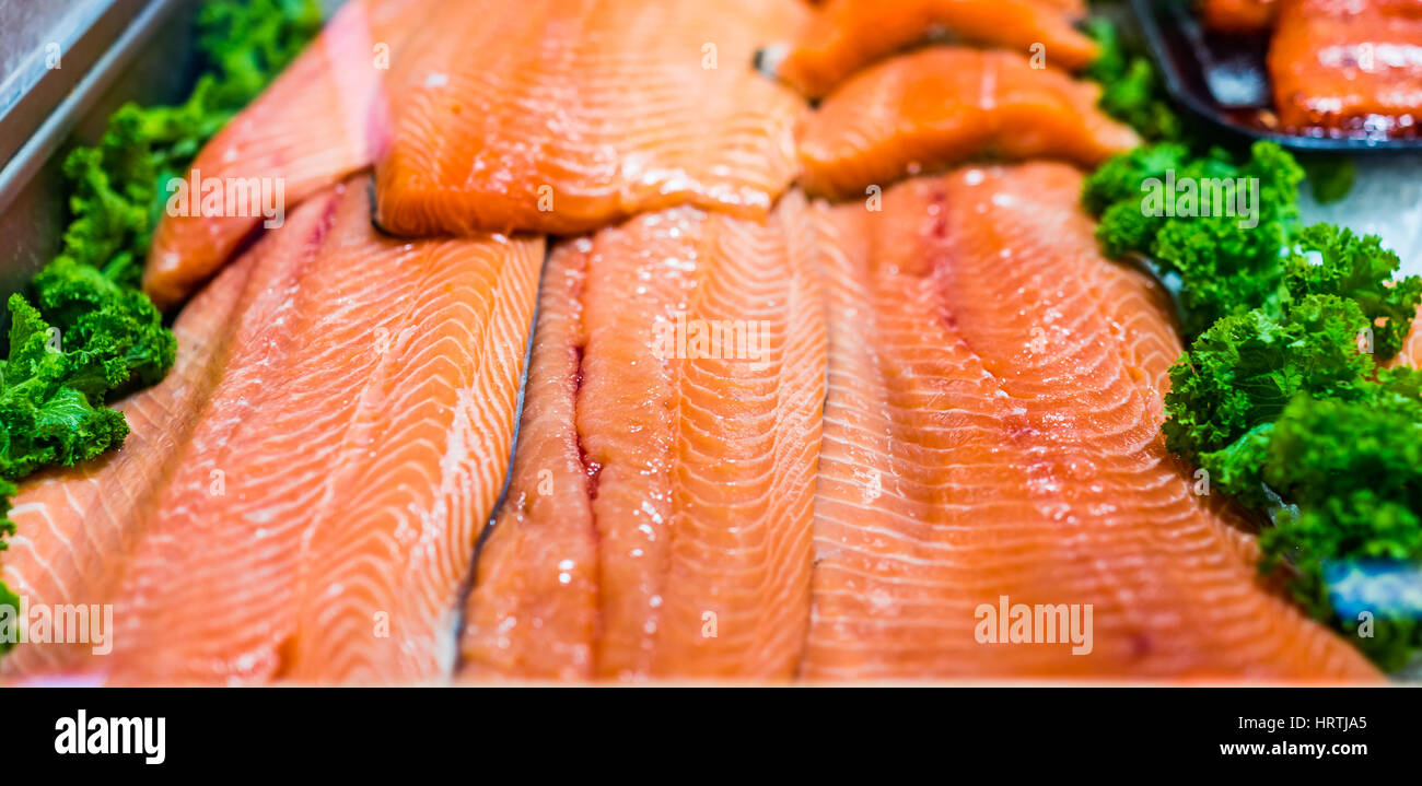 Seafood stand with cuts and filets of salmon on ice with kale leaves Stock Photo