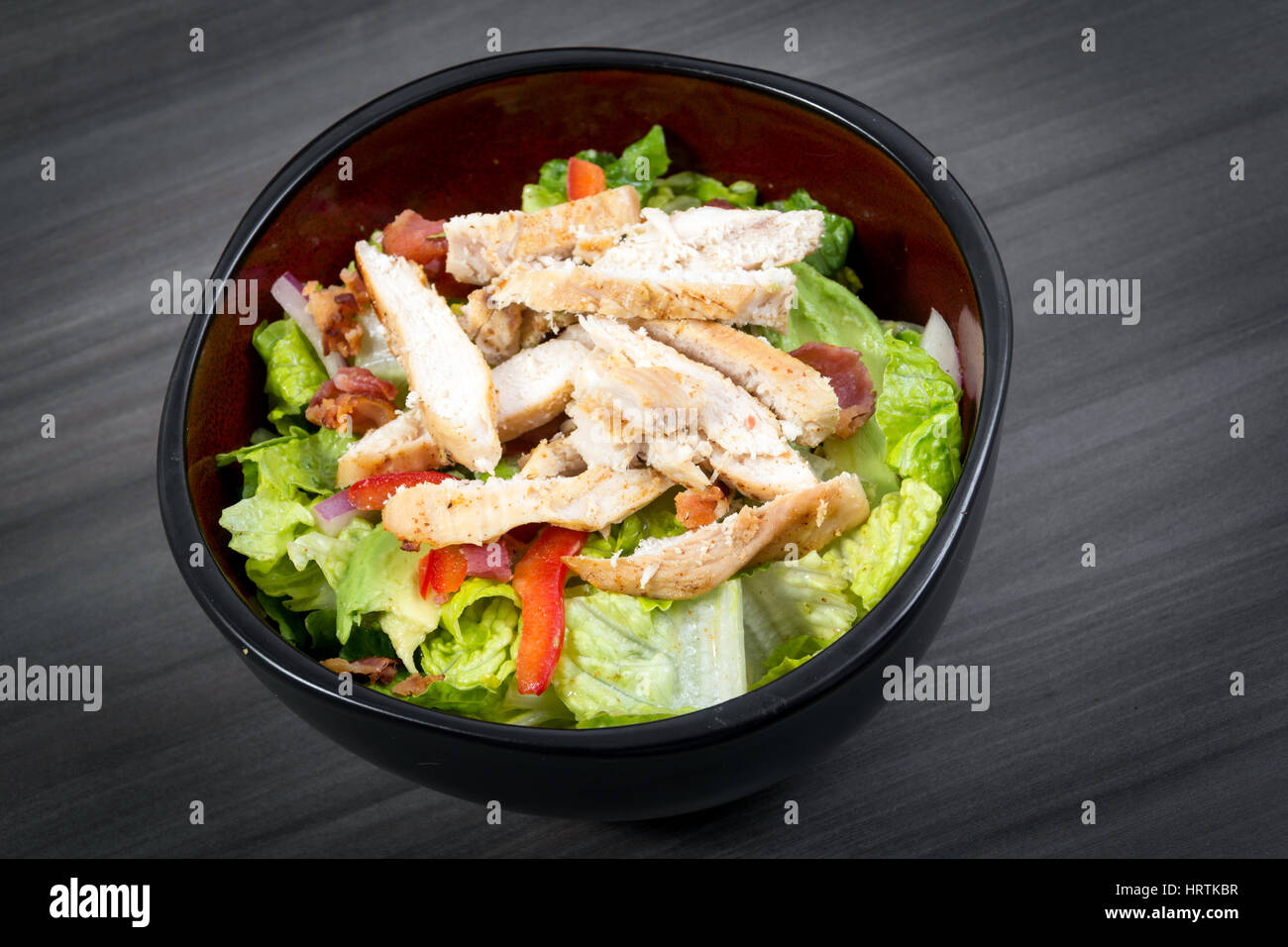 grilled chicken and bacon salad over a wood table closeup Stock Photo