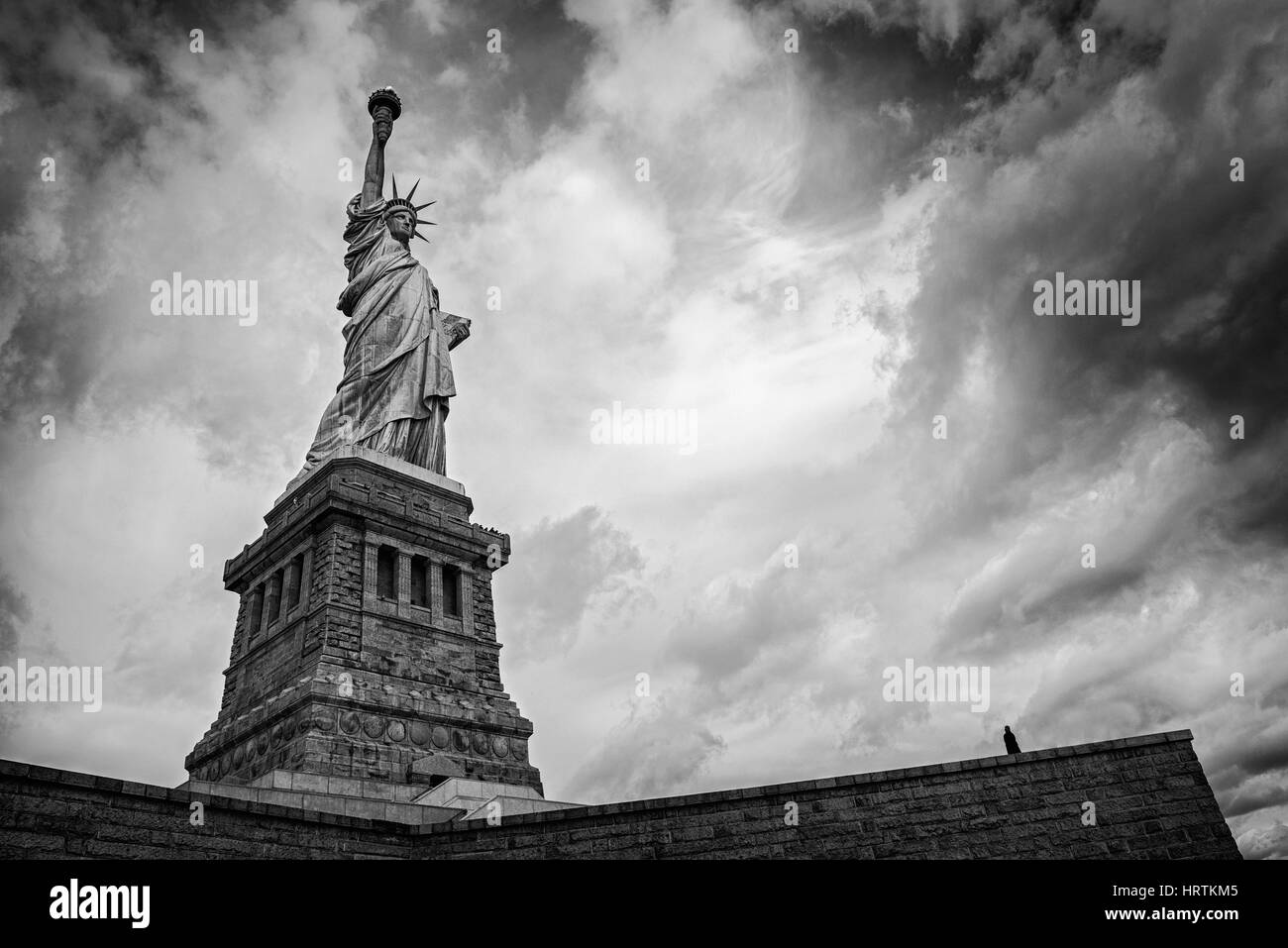 Sihouette of a lone figure looking up at the Statue of Liberty Stock Photo