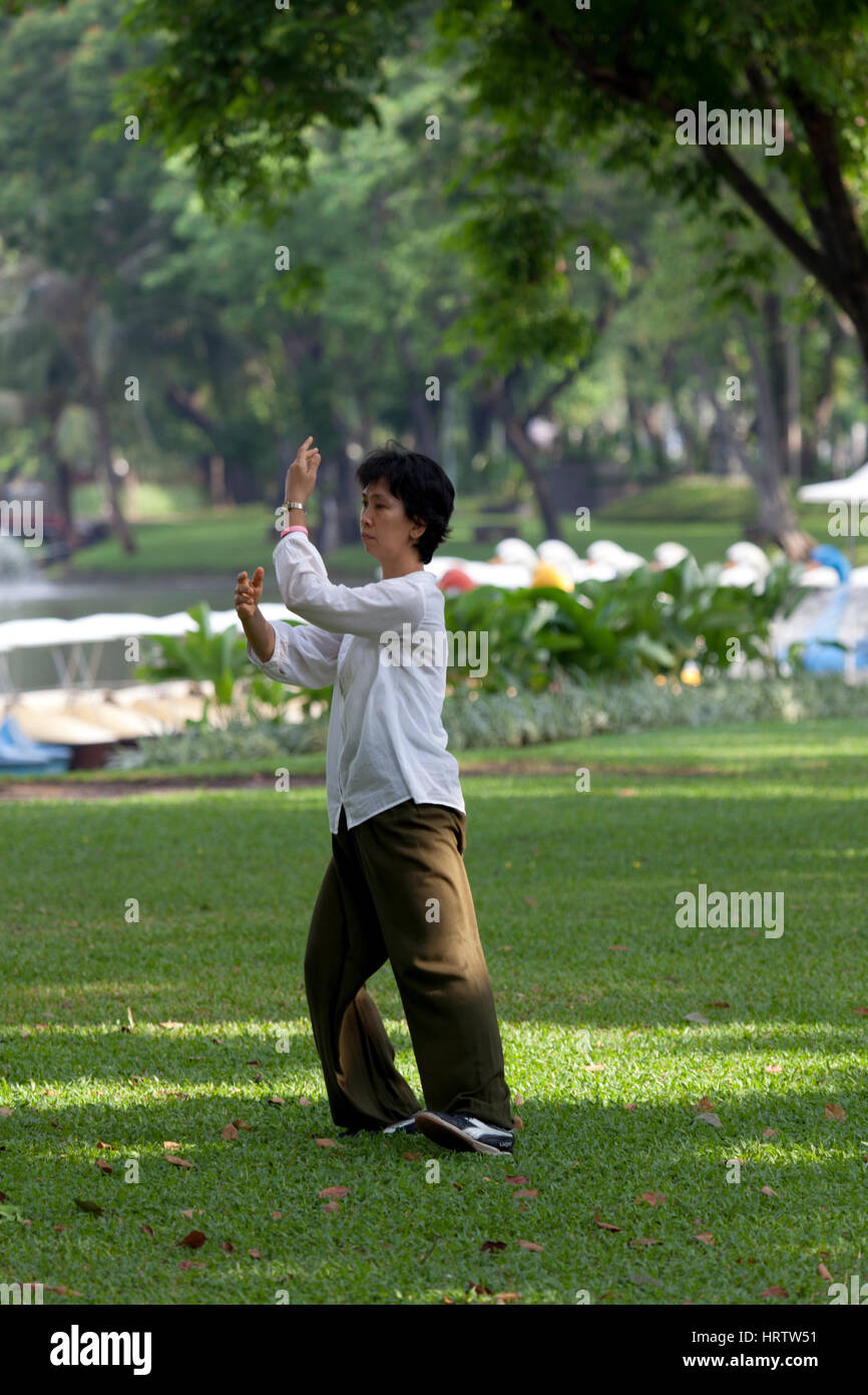 At Lumphini Park, an adult Thai woman practising tai-chi-chuan - a form of Chinese low stress training - in the early morning (Bangkok - Thailand). Stock Photo