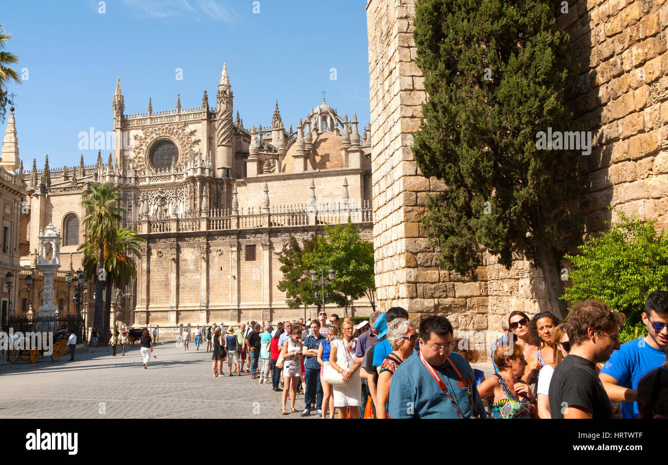 Line of tourists queueing to enter the Alcazar in Seville, Spain with the cathedral in background Stock Photo