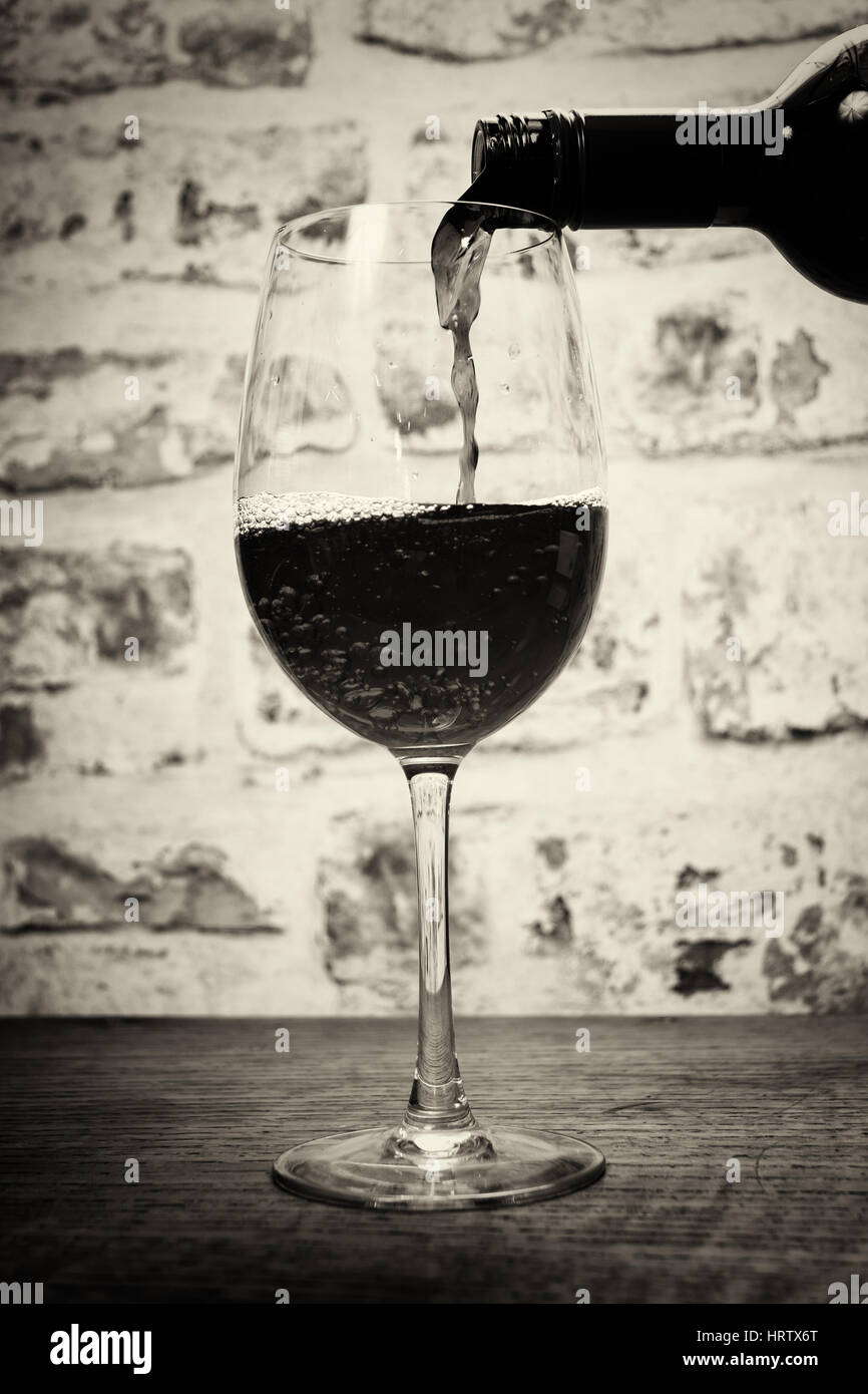 Glass of full bodied red wine being poured from bottle Stock Photo