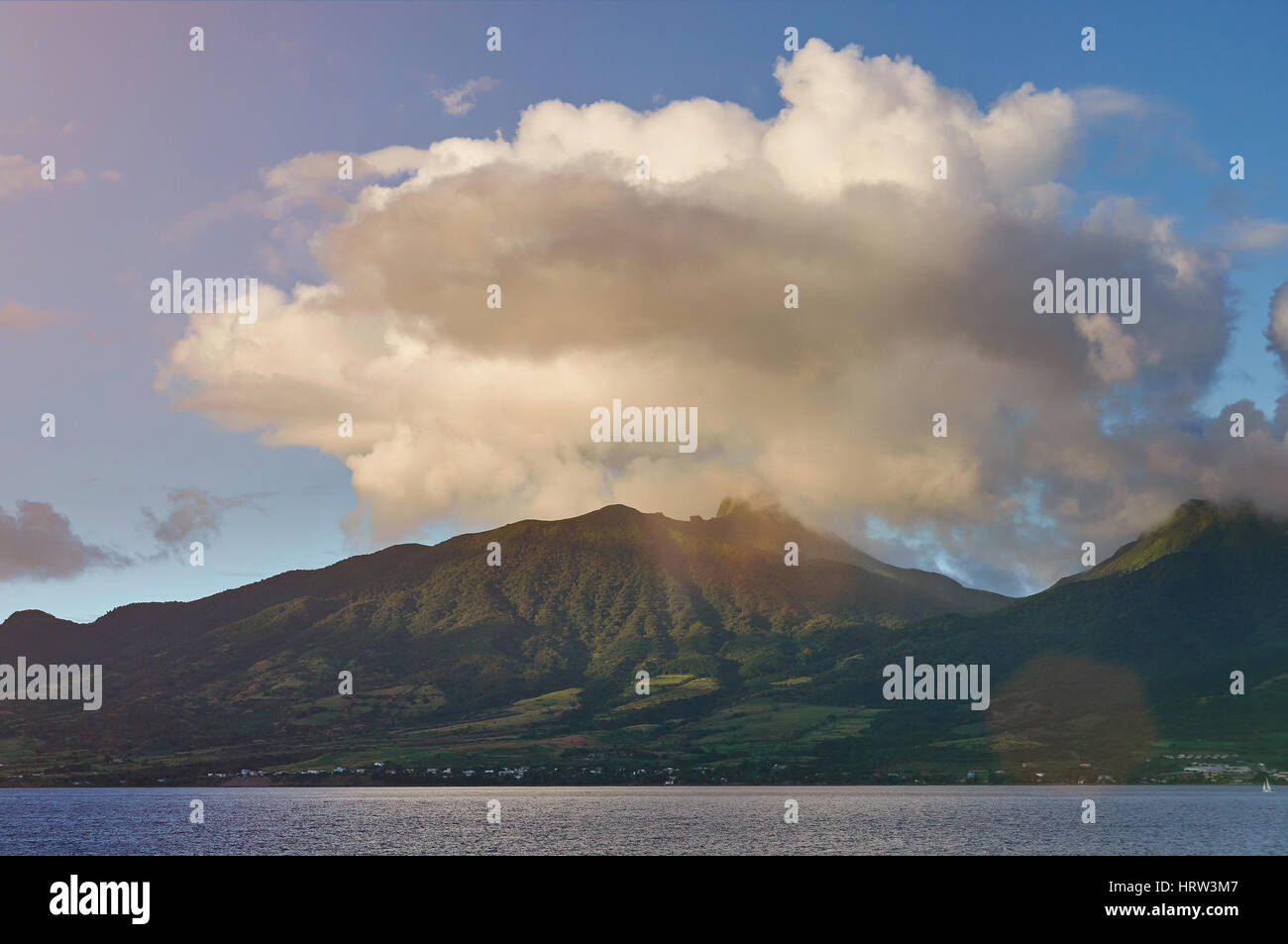Volcano on caribbean island on sunny day. Peak volcano in big white cloud Stock Photo
