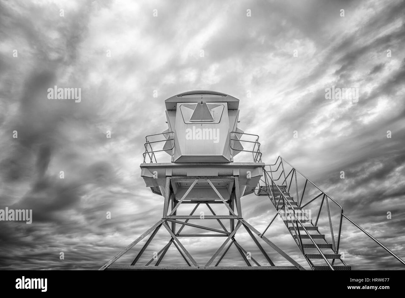 Low angle view of a lifeguard tower against a cloudy sky. Black and white image. Stock Photo