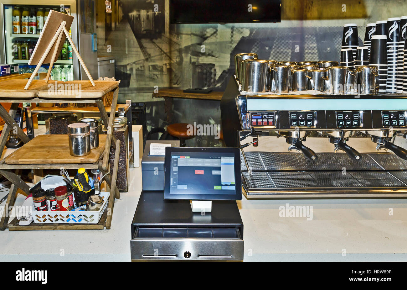 Automated counter at local coffee shop equipped with modern touch screen tablet solution on top of cash box and mobile printer as a POS terminal. Stock Photo