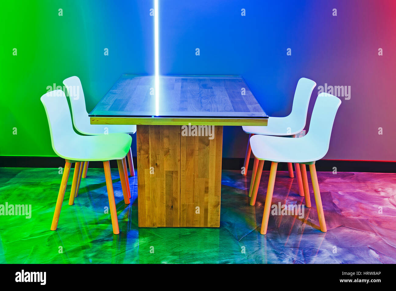 Multi colour light illumination at modern cafeteria with empty clean table and chairs waiting for customers on a reflecting floor. Stock Photo