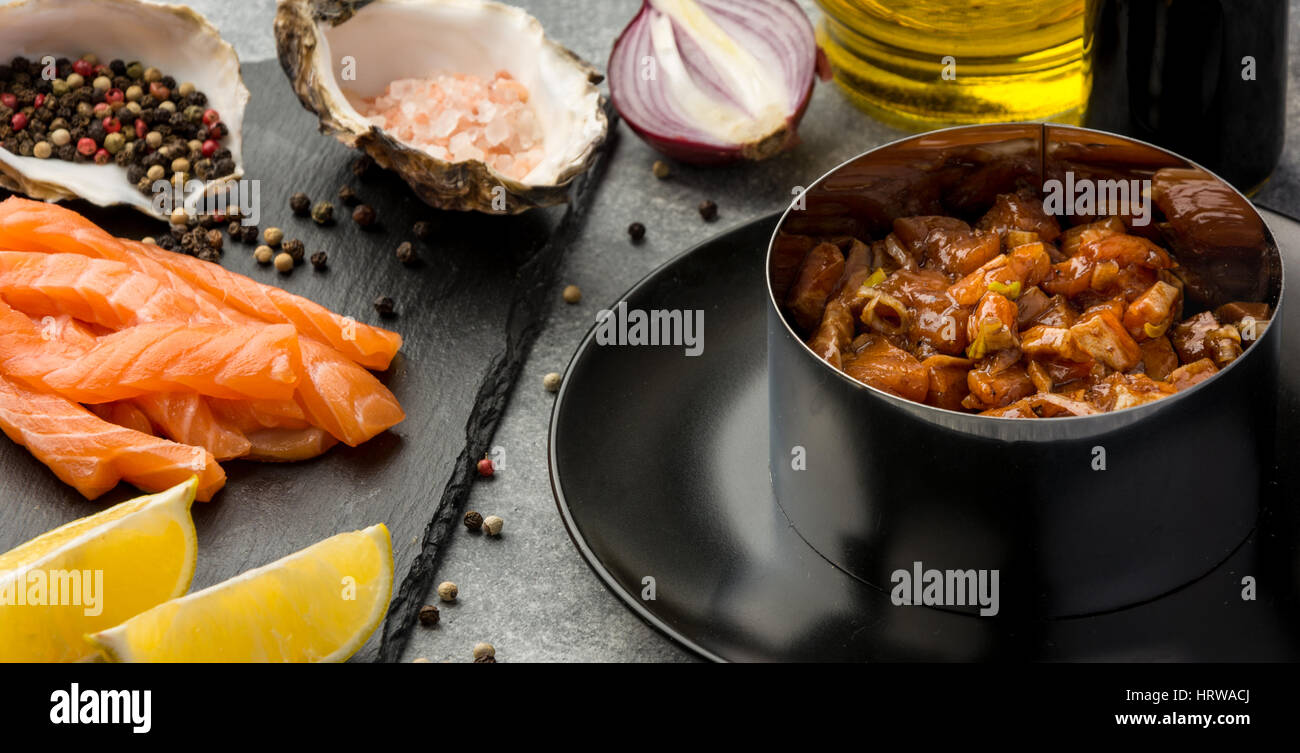 Delicious the tartare sauce from a salmon , rich in omega 3 oil, with aromatic herbs and spices with a lemon, on black background. Healthy and diet fo Stock Photo