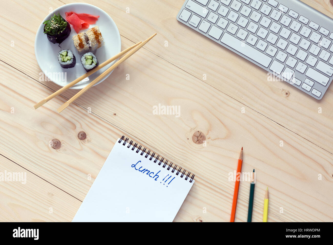 Savory looking fresh Sushi Set on white Plate with traditional Japanese Chopsticks Computer and Stationery opened Notepad with hand written Word Lunch Stock Photo