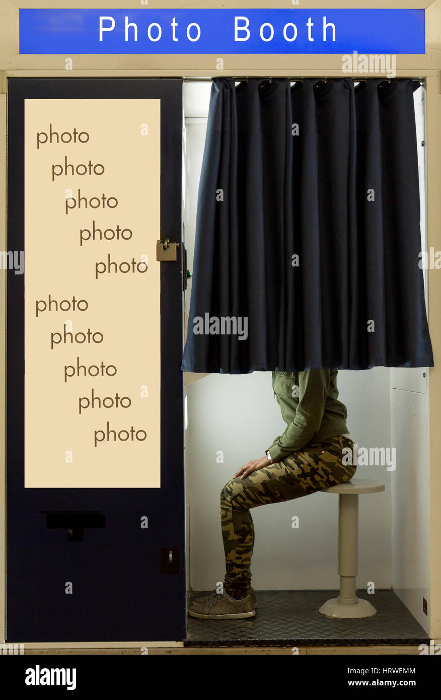 A person covered curtain sits in the photo booth. Woman makes the portrait inside photo booth. Automatic machine for the production of portrait photos Stock Photo