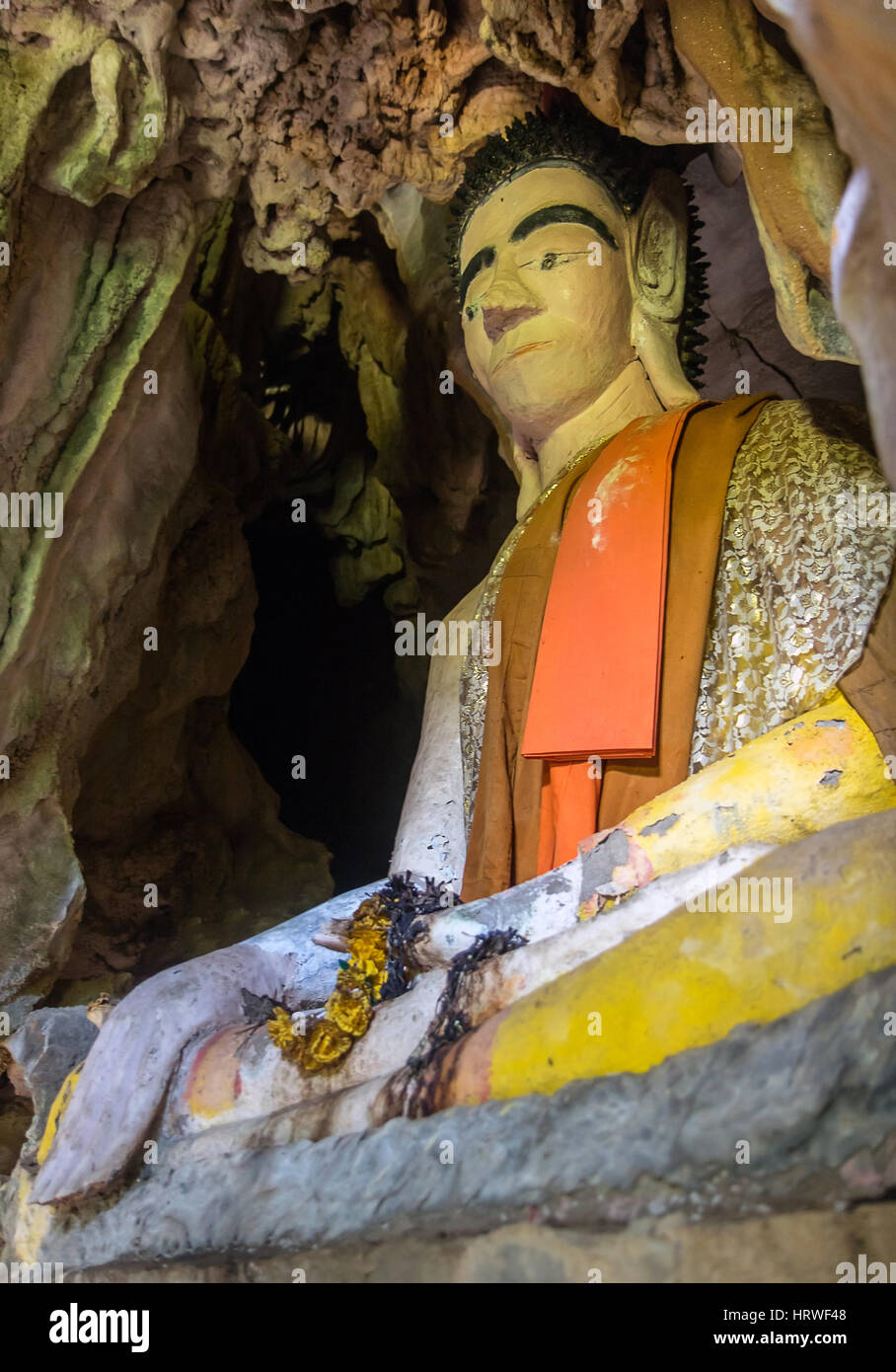 Buddha statue sitting in a cave. Dressed Statue of Buddha sitting in meditation posture, Laos. Stock Photo