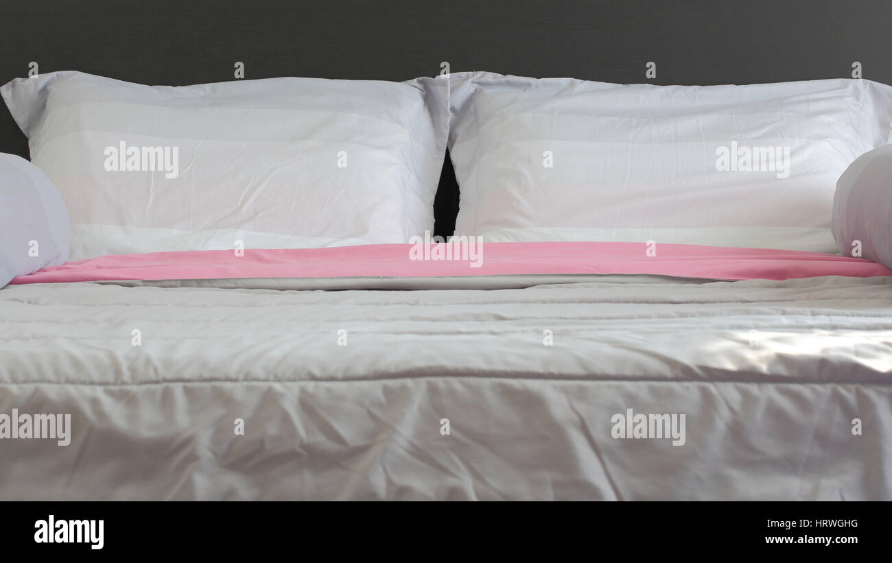 Close Up White And Pink Bedding Sheets And Pillow On Black Wooden