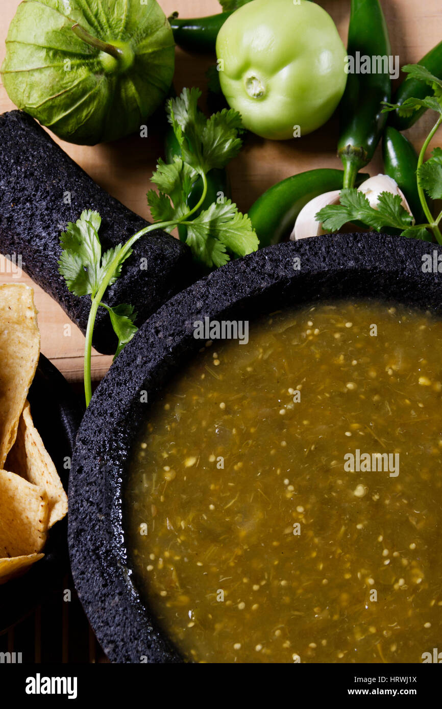 Stock image of mexican salsa verde on mortar and pestle with ingredients Stock Photo