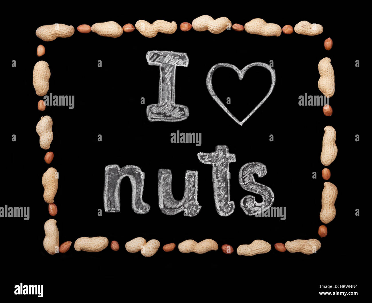 Frame of peanuts on a black background and chalk inscription 'I love nuts' Stock Photo