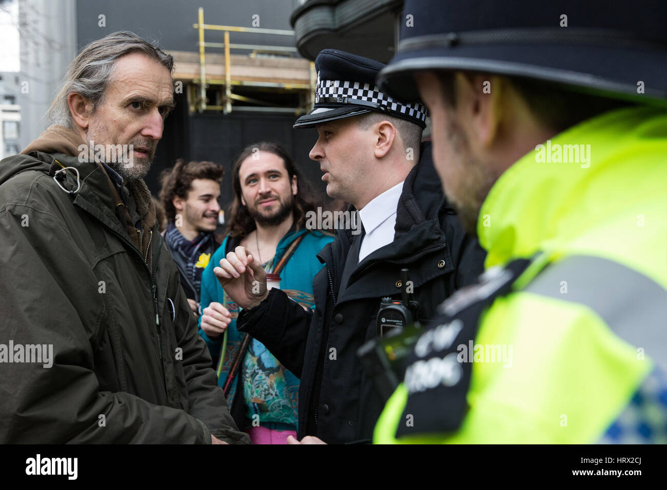 London, UK. 4th March, 2017. A police officer speaks to activist Roger Hallam before an action by Rising Up and Kings College Climate Emergency to decorate Kings College London with flowers and signs as part of a protest demanding that KCL divest from fossil fuels, invest in renewables and cease the banning and suspension of students for political activities. Stock Photo