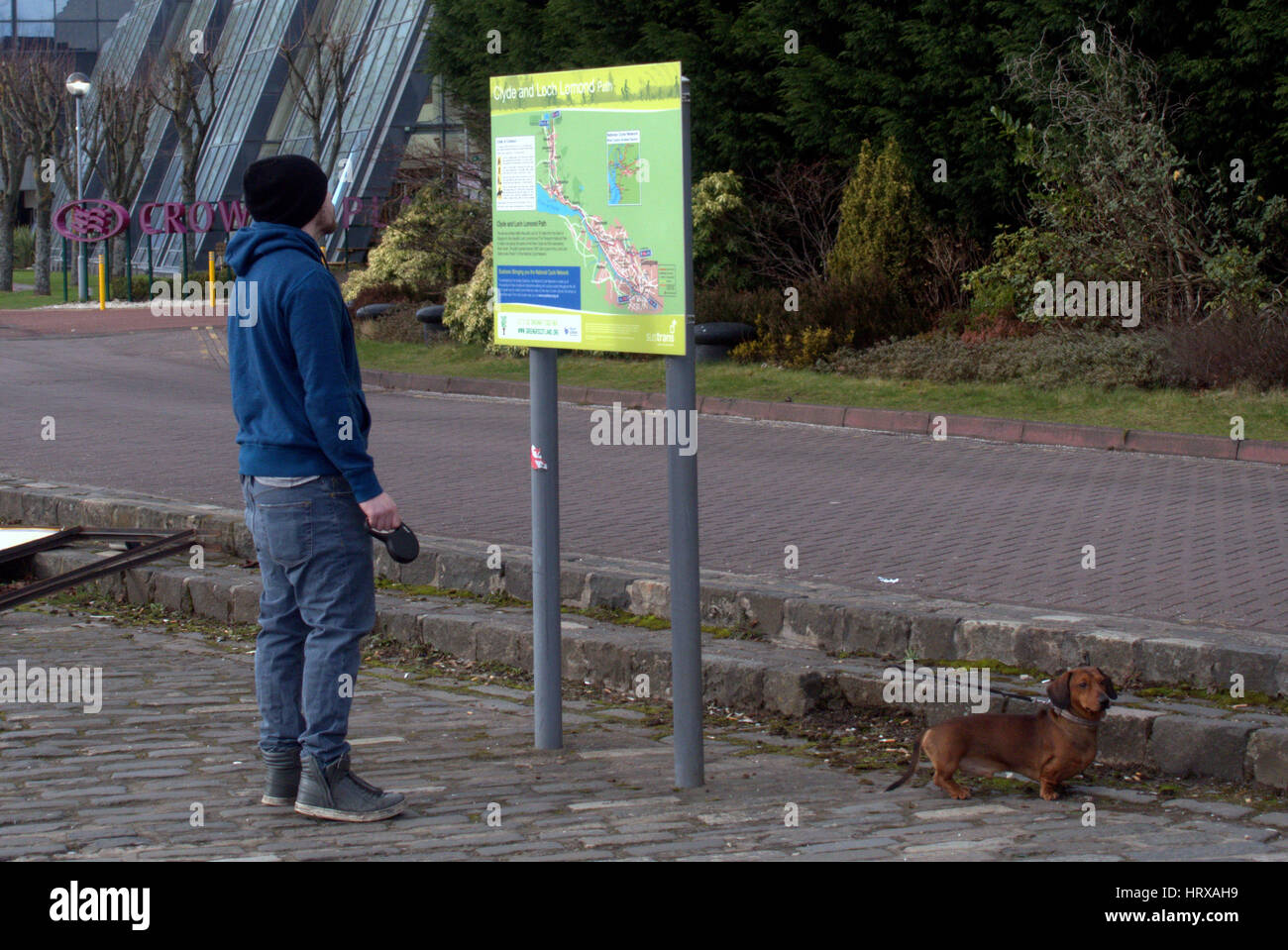 man with dog looking at tourist map of Glasgow Clyde walkway Stock Photo