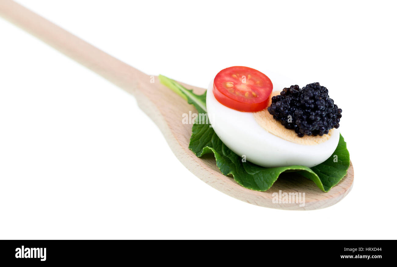 Lumpfish roe or black caviar on a half egg with sliced tomato creating a savoury snack. Stock Photo