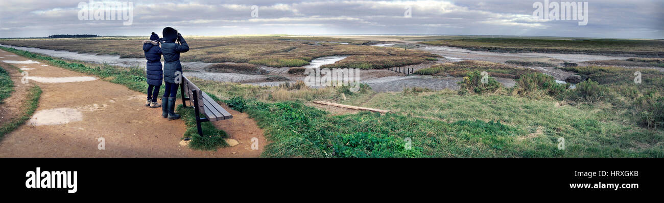 two women viewing thornham  marshes north norfolk england through binoculars Stock Photo