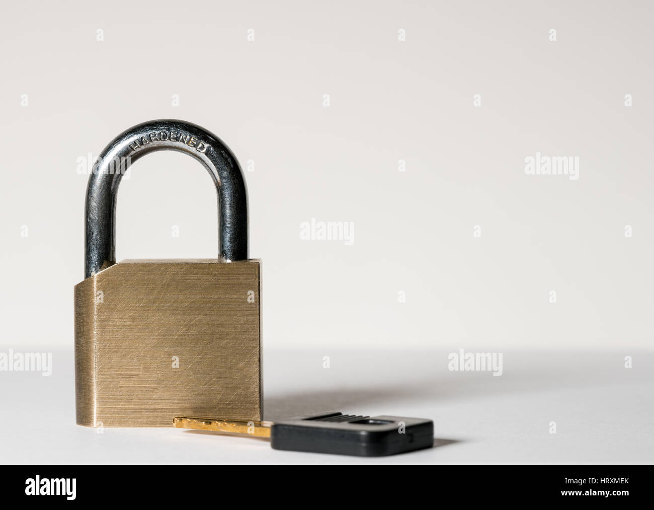 Close shot of a solid brass padlock with hardened hasp with key laying on surface Stock Photo