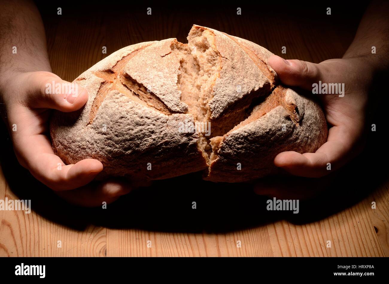 Breaking bread on a wooden table dark background Stock Photo