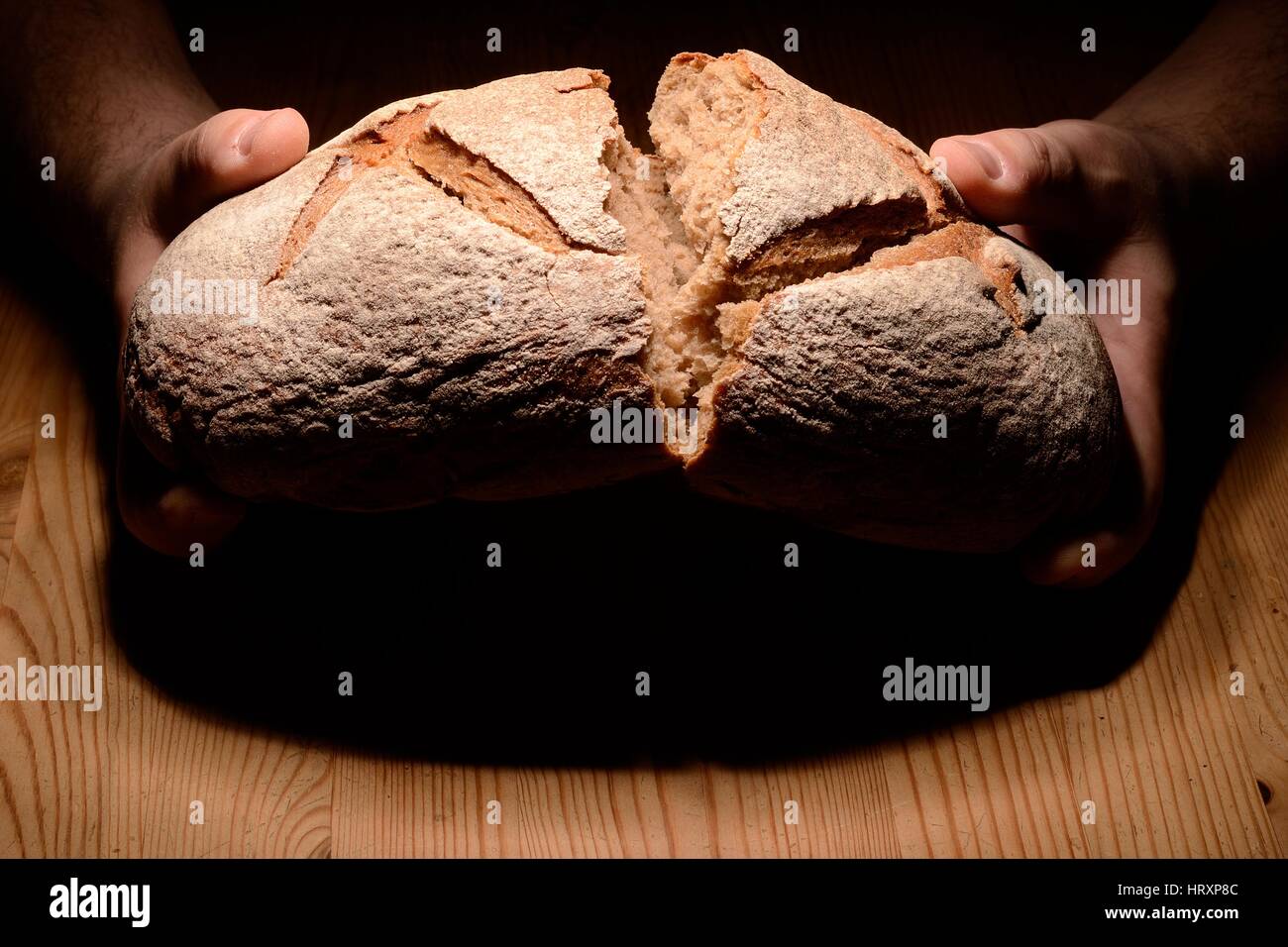Breaking bread on a wooden table dark background Stock Photo