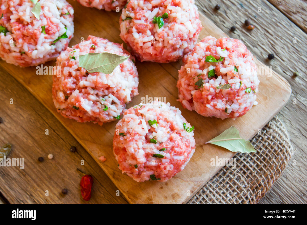 Cooking meatballs with vegetables, rice and spices on wooden cutting board close up Stock Photo