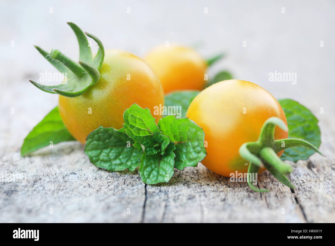 Fresh organic tomatoes with mint leaves on wooden surface Stock Photo